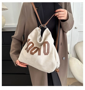 Detail of beige canvas tote bag with brown K010 patch and leather shoulder straps