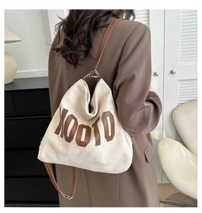 Close-up of beige canvas tote with brown XOOTO letters and slim leather straps