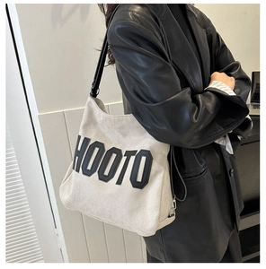 Detail of canvas tote bag showing wide black strap and large black HOOTO lettering