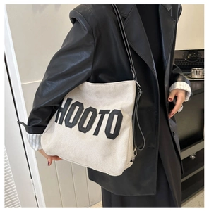 Detailed view of the HOOTO canvas tote bag with black leather straps on a female model