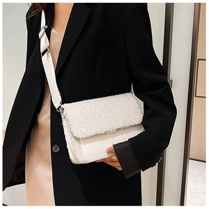 Detail of white plush lamb wool and leather stitching on crossbody bag with wide strap