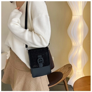 Modèle portant un petit sac à bandoulière noir pour téléphone avec rabat en strass
