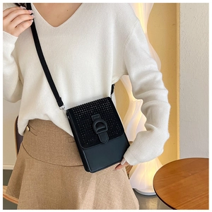 Détail du sac de téléphone noir à bandoulière avec rabat clouté et boucle métallique en D