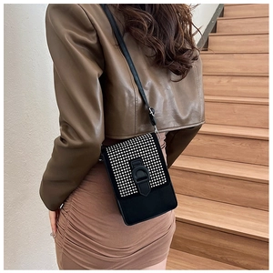 Détail d'un petit sac bandoulière noir avec clous argentés et bandoulière réglable