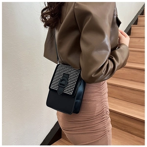 Détail du petit sac bandoulière noir avec rivets argentés porté par un mannequin