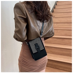 Détail du petit sac bandoulière noir avec clous argentés et finition mate sur modèle