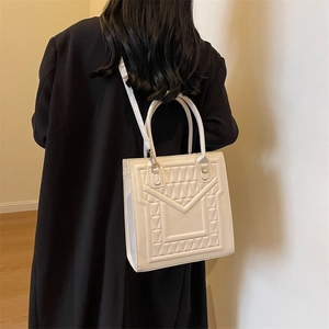 Chic white square tote bag with geometric embossed texture and circular handles