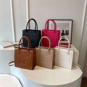Minimalist square tote bag with geometric quilting in five colors on a display stand