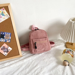 Pink corduroy mini backpack with front pocket displayed in a cozy lifestyle setting