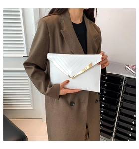 Gros plan sur pochette enveloppe blanche avec garniture en métal doré en V et coutures