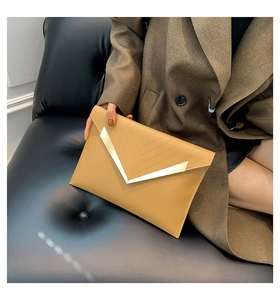 Détail de la pochette enveloppe camel avec logo en métal V doré et coutures surpiquées