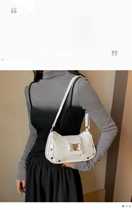 Detail of white glossy leather underarm bag featuring heart-shaped gold buckle and studs