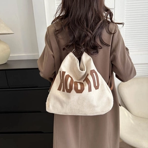 Minimalist cream canvas tote bag with brown XOOTO embroidery worn by a model in lifestyle setting