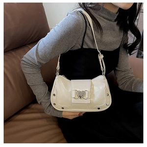 Detail of creamy white shoulder bag with silver heart lock and stud accents on model