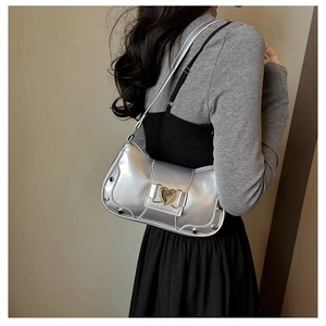 Detail of silver metallic underarm bag with heart buckle and studs on model shoulder