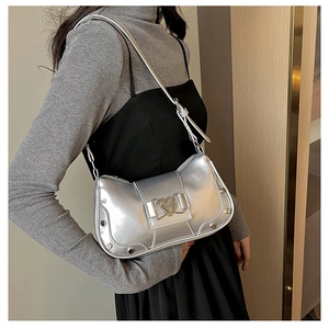 Detail of silver metallic hobo bag with heart buckle and studs shown on a model