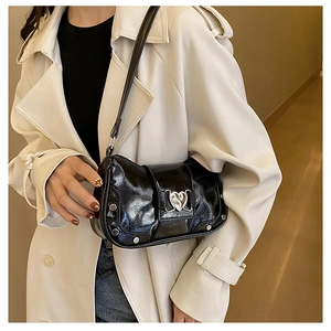 Detail of black glossy faux leather shoulder bag with a silver hollow heart metal buckle