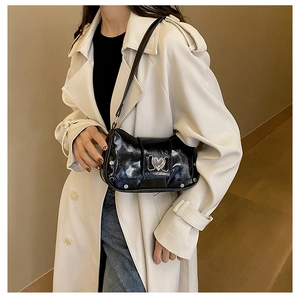 Detail of glossy black underarm bag with silver heart buckle and metal rivet studs