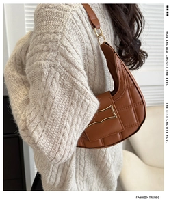 Detailed view of brown quilted crescent bag with a decorative gold buckle and wide strap