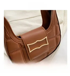 Close-up of brown quilted leather crescent bag with a rectangular gold metal buckle