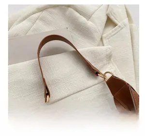 Detail of brown leather shoulder strap with gold metal rings and stitching