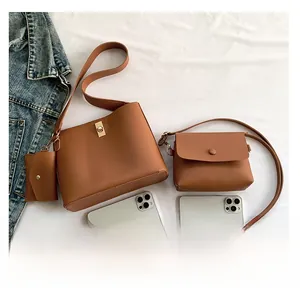 Detailed set of brown leather bucket bag, crossbody bag, and mini coin purse on white fabric