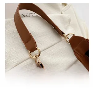 Detail of crescent bag featuring brown leather strap with gold metal ring buckle