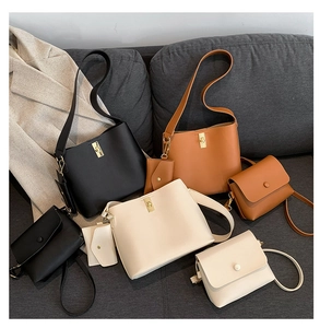 Detailed set of leather shoulder bags in black, camel, and white on a stylish sofa