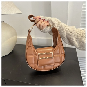 Detail of a brown quilted crescent bag featuring a gold buckle and textured leather finish