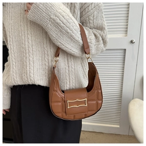 Detail of a brown crescent shoulder bag with quilted leather and a gold metal buckle