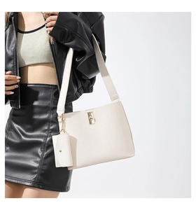 Close-up of cream textured tote bag with golden twist lock and mini pouch accessory