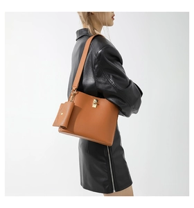 Detail of vintage brown bucket bag with gold lock buckle and matching mini pouch accessory