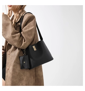 Detail of black faux leather tote bag with gold twist lock and matching envelope pouch