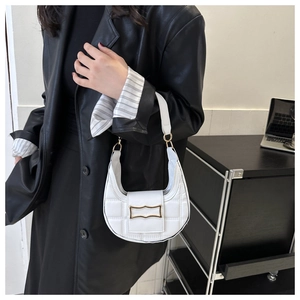 Detail of white quilted crescent bag with gold buckle on black leather suit backdrop