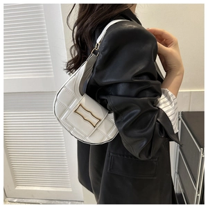 Close-up of a white quilted crescent shoulder bag with a gold metal buckle detail