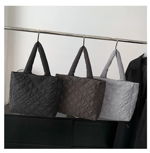 Vue détaillée des sacs fourre-tout matelassés noirs, marrons et gris suspendus au support
