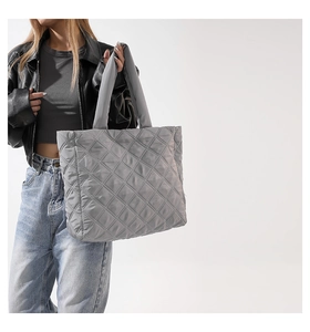 Détail d'un sac cabas gris matelassé avec motif à losanges porté par un mannequin
