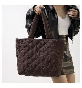 Vue latérale du mannequin portant un grand sac cabas matelassé marron café à losanges