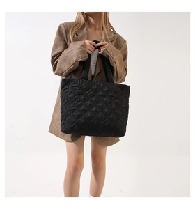 Sac fourre-tout matelassé noir tendance porté avec un costume marron en studio photo