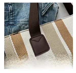 Close-up of the reinforced stitching and leather handle attachment on a canvas tote bag