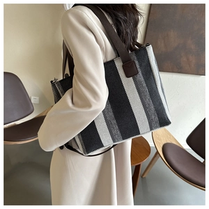 Detail view of large canvas tote bag with vertical stripes and brown shoulder straps