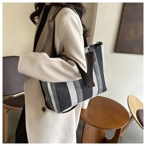 Detailed side view of large striped woven tote bag worn on shoulder for commute