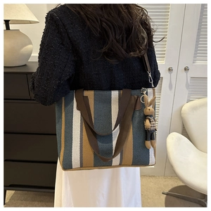 Vertical striped canvas tote bag detail featuring colorful stripes and a plush rabbit charm
