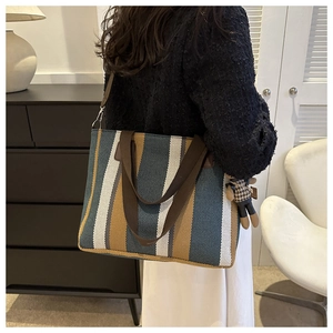 Detail of striped canvas tote bag in blue and beige with a cute bear charm on shoulder
