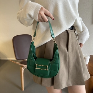 Deep green quilted crescent shoulder bag with gold clasp held in a minimalist setting