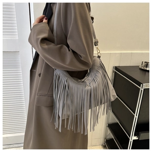 Detail view of grey hobo bucket bag with stylish long fringe and gold metal hardware