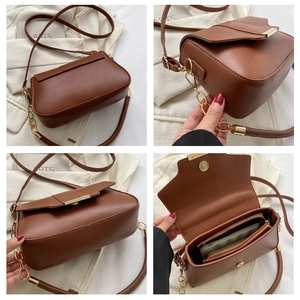 Detail view of brown vintage square bag featuring gold clasp and chain strap with interior