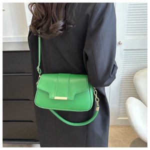 Detail view of vibrant green leather shoulder bag with gold hardware and dual strap design