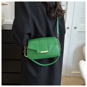 Green square crossbody bag with gold metal buckle shown on a model's shoulder