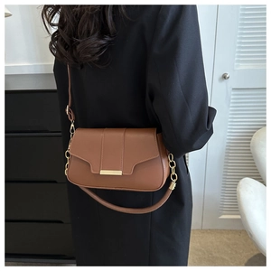 Brown faux leather crossbody bag with gold buckle and chain strap shown on a black blazer